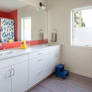 Foto di una stanza da bagno per bambini moderna di medie dimensioni con ante lisce, ante bianche, vasca/doccia, piastrelle arancioni, piastrelle in gres porcellanato, pareti bianche, pavimento in linoleum, lavabo sottopiano, top in vetro riciclato e pavimento multicolore