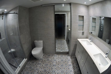 Foto di una stanza da bagno padronale design di medie dimensioni con ante lisce, ante grigie, doccia alcova, WC monopezzo, pareti marroni, pavimento in linoleum, lavabo sottopiano e top in superficie solida
