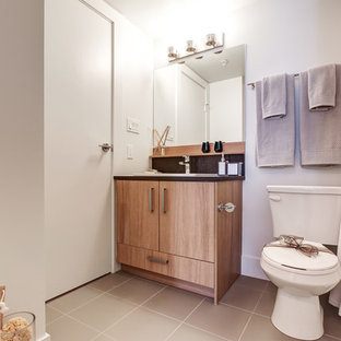 Kleines Skandinavisches Badezimmer mit flächenbündigen Schrankfronten, hellbraunen Holzschränken, Toilette mit Aufsatzspülkasten, schwarzen Fliesen, lila Wandfarbe, Keramikboden, Quarzwerkstein-Waschtisch und beigem Boden in Calgary