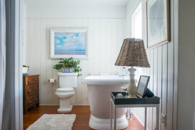 Diseño de cuarto de baño principal tradicional grande con bañera exenta, ducha empotrada, sanitario de una pieza, paredes blancas, suelo de madera en tonos medios y lavabo con pedestal