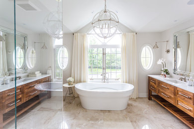На фото: ванная комната в стиле неоклассика (современная классика) с врезной раковиной, фасадами цвета дерева среднего тона, отдельно стоящей ванной и белой плиткой