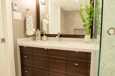 Modelo de cuarto de baño principal actual de tamaño medio con lavabo bajoencimera, armarios con paneles lisos, puertas de armario de madera oscura, encimera de cuarzo compacto y baldosas y/o azulejos beige