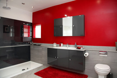 Photo of a medium sized contemporary shower room bathroom in Other with flat-panel cabinets, grey cabinets, a freestanding bath, a walk-in shower, a one-piece toilet, red walls, a vessel sink, solid surface worktops, grey floors, an open shower and grey worktops.