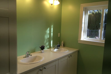 Mid-sized eclectic 3/4 ceramic tile bathroom photo in Portland with shaker cabinets, white cabinets, a two-piece toilet, green walls, a drop-in sink and solid surface countertops