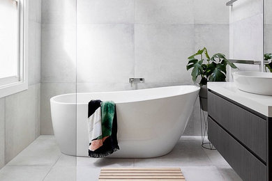 Example of a trendy gray tile and porcelain tile gray floor and porcelain tile freestanding bathtub design in Toronto with flat-panel cabinets, black cabinets, gray walls, a vessel sink and white countertops