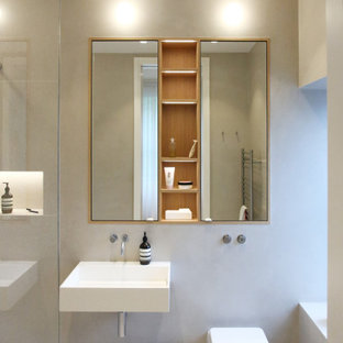 This is an example of a small contemporary ensuite bathroom in London with a corner shower, a wall mounted toilet, grey tiles, porcelain tiles, porcelain flooring, a wall-mounted sink and grey floors.