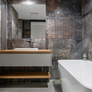 Design ideas for a contemporary bathroom in Sunshine Coast with flat-panel cabinets, grey cabinets, a freestanding tub, beige tile, black tile, brown tile, gray tile, a drop-in sink, wood benchtops, grey floor and brown benchtops.