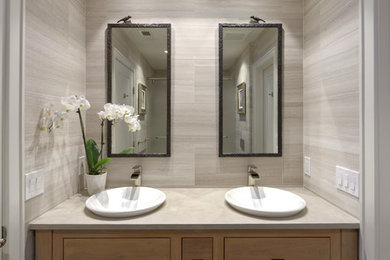 Example of a mid-sized trendy kids' gray tile and marble tile slate floor and black floor bathroom design in DC Metro with furniture-like cabinets, medium tone wood cabinets, a wall-mount toilet, gray walls, a vessel sink, limestone countertops and gray countertops