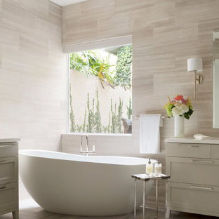 Freestanding bathtub - mid-sized contemporary master beige tile and stone slab marble floor freestanding bathtub idea in Miami with shaker cabinets, gray cabinets and solid surface countertops