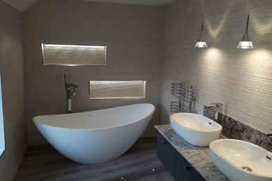 This is an example of a large contemporary family bathroom in West Midlands with a freestanding bath, a wall mounted toilet, white tiles, ceramic tiles, laminate floors, quartz worktops, grey floors and multi-coloured worktops.