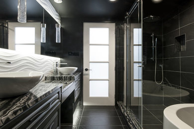 他の地域にあるラグジュアリーな小さなコンテンポラリースタイルのおしゃれなマスターバスルーム (レイズドパネル扉のキャビネット、黒いキャビネット、置き型浴槽、コーナー設置型シャワー、壁掛け式トイレ、黒いタイル、セラミックタイル、黒い壁、セラミックタイルの床、ベッセル式洗面器、御影石の洗面台) の写真