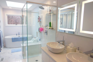 Cette image montre une salle de bain design de taille moyenne avec un placard à porte plane, des portes de placard blanches, une baignoire indépendante, une douche à l'italienne, WC à poser, un carrelage blanc, une vasque et un plan de toilette en quartz modifié.