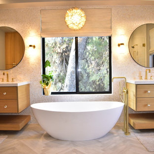Foto de cuarto de baño principal, actual, con puertas de armario de madera oscura, bañera exenta, lavabo integrado, encimeras blancas, armarios con paneles lisos, baldosas y/o azulejos beige, paredes beige, suelo de madera clara y suelo beige