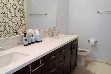 Mid-sized trendy white tile and ceramic tile brown floor bathroom photo in Orange County with flat-panel cabinets, dark wood cabinets, a two-piece toilet, gray walls and quartz countertops