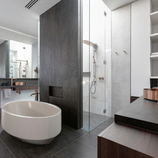 Design ideas for a large contemporary master bathroom in Melbourne with stone tile, a hinged shower door, flat-panel cabinets, dark wood cabinets, a freestanding tub, a curbless shower, gray tile, a vessel sink, grey floor and black benchtops.