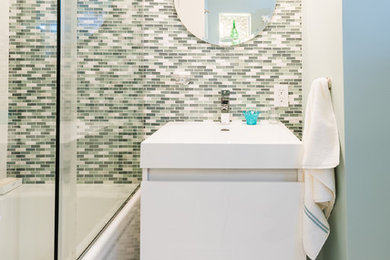 Ispirazione per una stanza da bagno design con ante lisce, ante bianche, vasca/doccia, WC monopezzo, piastrelle verdi, piastrelle a listelli, pavimento in gres porcellanato, lavabo integrato e pareti verdi