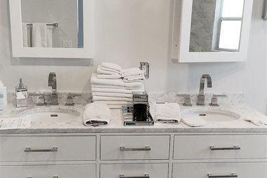 Large trendy master porcelain tile and gray floor bathroom photo in Los Angeles with flat-panel cabinets, white cabinets, white walls, an undermount sink and marble countertops