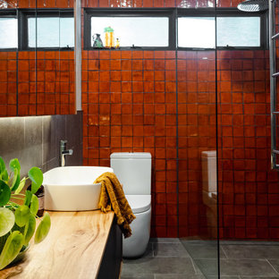 This is an example of a small contemporary master bathroom in Melbourne with flat-panel cabinets, medium wood cabinets, an open shower, a one-piece toilet, gray tile, porcelain tile, grey walls, porcelain floors, a vessel sink, wood benchtops, grey floor, an open shower, a niche, a single vanity and a floating vanity.