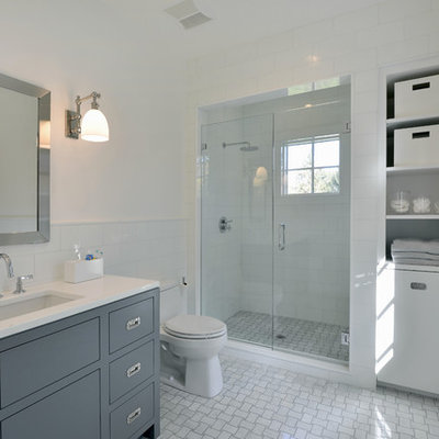 Transitional white tile alcove shower photo in New York with an undermount sink, flat-panel cabinets, blue cabinets, a one-piece toilet and white walls