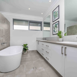 Large contemporary bathroom in Perth with flat-panel cabinets, white cabinets, a freestanding tub, porcelain tile, white walls, a drop-in sink, white benchtops, gray tile and grey floor.