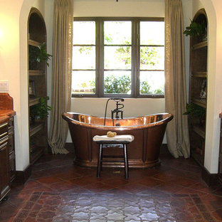 Foto di un'ampia stanza da bagno mediterranea con ante con bugna sagomata, ante in legno bruno, vasca freestanding, WC monopezzo, piastrelle beige, piastrelle marroni, piastrelle multicolore, piastrelle rosse, piastrelle in gres porcellanato, pareti beige, pavimento in gres porcellanato, lavabo da incasso, top in granito e pavimento rosso