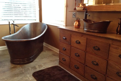 Freestanding bathtub - mid-sized traditional freestanding bathtub idea in Phoenix with a vessel sink, flat-panel cabinets and medium tone wood cabinets