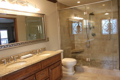Alcove shower - mid-sized traditional 3/4 beige tile and stone tile limestone floor and beige floor alcove shower idea in Chicago with raised-panel cabinets, medium tone wood cabinets, a two-piece toilet, beige walls, an undermount sink and granite countertops