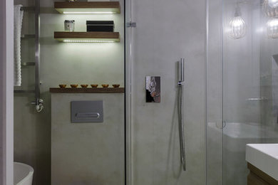 ロンドンにある高級な中くらいなエクレクティックスタイルのおしゃれなマスターバスルーム (フラットパネル扉のキャビネット、淡色木目調キャビネット、置き型浴槽、オープン型シャワー、壁掛け式トイレ、マルチカラーのタイル、グレーの壁、セラミックタイルの床、横長型シンク、グレーの床、引戸のシャワー) の写真