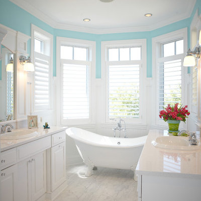Claw-foot bathtub - large traditional master marble floor and white floor claw-foot bathtub idea in Grand Rapids with a drop-in sink, raised-panel cabinets, white cabinets, quartzite countertops, a two-piece toilet and blue walls