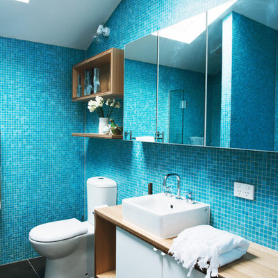 Large trendy master blue tile and mosaic tile ceramic tile bathroom photo in Melbourne with a vessel sink, flat-panel cabinets, white cabinets, wood countertops and a two-piece toilet