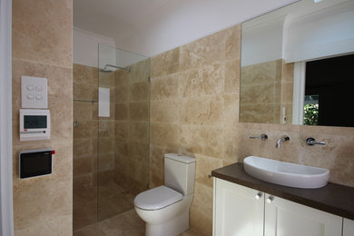 Foto på ett funkis badrum, med en toalettstol med hel cisternkåpa och travertin golv