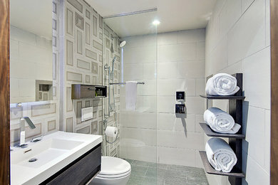 Inredning av ett modernt litet badrum, med ett väggmonterat handfat, en kantlös dusch, en vägghängd toalettstol, stenkakel och klinkergolv i porslin