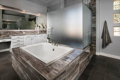 Example of a large transitional master gray tile and porcelain tile porcelain tile bathroom design in Las Vegas with recessed-panel cabinets, white cabinets, a one-piece toilet, gray walls, an undermount sink and granite countertops