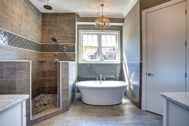 他の地域にある広いトラディショナルスタイルのおしゃれなマスターバスルーム (置き型浴槽、オープン型シャワー、茶色いタイル、磁器タイル、茶色い壁、磁器タイルの床、大理石の洗面台) の写真