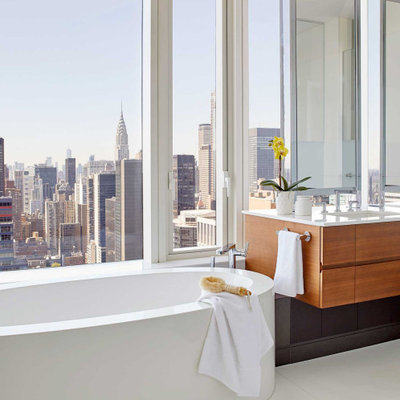 Freestanding bathtub - contemporary white floor freestanding bathtub idea in New York with flat-panel cabinets, medium tone wood cabinets, an undermount sink, white countertops and a floating vanity