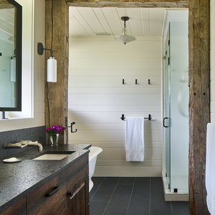 Foto de cuarto de baño principal, ecléctico, con armarios tipo mueble, puertas de armario de madera en tonos medios, bañera exenta, ducha empotrada, baldosas y/o azulejos blancos, paredes blancas, suelo de baldosas de cerámica, lavabo bajoencimera, encimera de cuarcita, suelo negro y ducha con puerta con bisagras