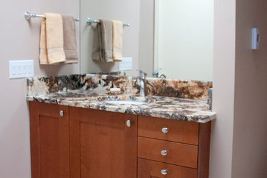 Cette photo montre une salle de bain principale chic en bois brun de taille moyenne avec un placard à porte shaker, un carrelage beige, des carreaux de céramique, un mur beige, un sol en carrelage de céramique, un lavabo encastré et un plan de toilette en granite.