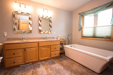Cette image montre une salle de bain principale craftsman en bois brun de taille moyenne avec un placard avec porte à panneau surélevé, une baignoire indépendante, un mur beige, un sol en calcaire, un lavabo intégré, un plan de toilette en stratifié et un sol beige.
