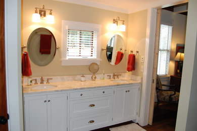 ローリーにあるトラディショナルスタイルのおしゃれな浴室 (オーバーカウンターシンク、落し込みパネル扉のキャビネット、白いキャビネット、ベージュの壁) の写真