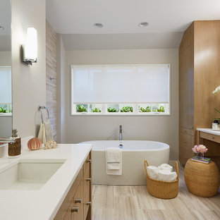 Example of an ornate freestanding bathtub design in Minneapolis with an undermount sink, flat-panel cabinets, medium tone wood cabinets and beige walls