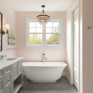 Freestanding bathtub - coastal master white tile and subway tile gray floor freestanding bathtub idea in Minneapolis with shaker cabinets, gray cabinets, pink walls, an undermount sink and white countertops
