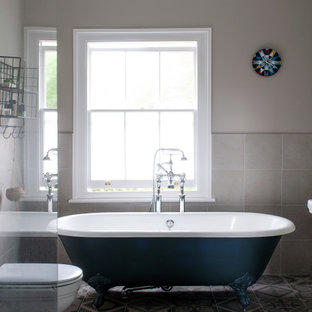 Medium sized traditional ensuite bathroom in London with a freestanding bath, a two-piece toilet, beige walls, mosaic tile flooring and grey floors.