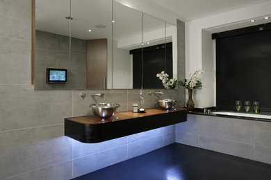 Diseño de cuarto de baño actual grande con encimera de madera, bañera encastrada, ducha empotrada, baldosas y/o azulejos grises y paredes grises
