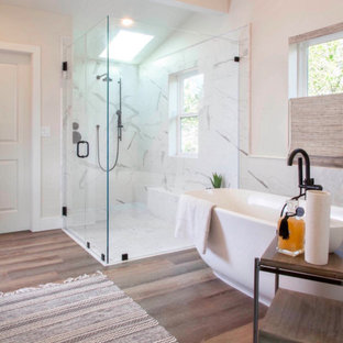 Design ideas for a large beach style master bathroom in San Diego with flat-panel cabinets, distressed cabinets, a freestanding tub, a curbless shower, a one-piece toilet, white tile, porcelain tile, white walls, laminate floors, an undermount sink, engineered quartz benchtops, beige floor, a hinged shower door, white benchtops, a shower seat, a double vanity, a built-in vanity and vaulted.