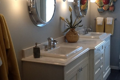 Example of a mid-sized transitional master white tile and ceramic tile porcelain tile corner shower design in Vancouver with a drop-in sink, furniture-like cabinets, quartzite countertops, a two-piece toilet, gray walls and white cabinets