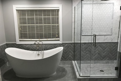 Réalisation d'une grande salle de bain principale tradition avec une baignoire indépendante, une douche d'angle, un carrelage gris, un carrelage blanc, un carrelage métro, un mur gris, un sol en carrelage de porcelaine, un sol gris et une cabine de douche à porte battante.