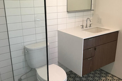 ロサンゼルスにある小さなコンテンポラリースタイルのおしゃれなバスルーム (浴槽なし) (分離型トイレ、白い壁、セメントタイルの床、アンダーカウンター洗面器、マルチカラーの床、オープンシャワー、フラットパネル扉のキャビネット、中間色木目調キャビネット、アルコーブ型シャワー、白いタイル、セラミックタイル、人工大理石カウンター) の写真