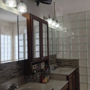 Example of a large transitional master pebble tile ceramic tile doorless shower design in Columbus with recessed-panel cabinets, dark wood cabinets, solid surface countertops and beige walls