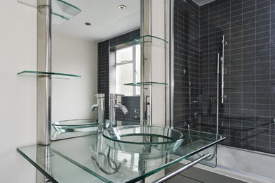 Foto de cuarto de baño actual con encimera de vidrio y lavabo sobreencimera