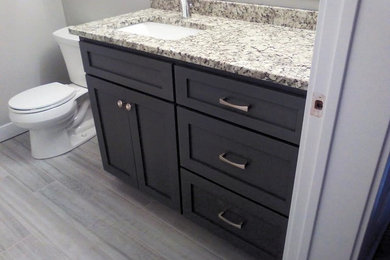 Example of a mid-sized transitional 3/4 light wood floor bathroom design in Other with shaker cabinets, gray cabinets, a one-piece toilet, gray walls, an undermount sink and granite countertops